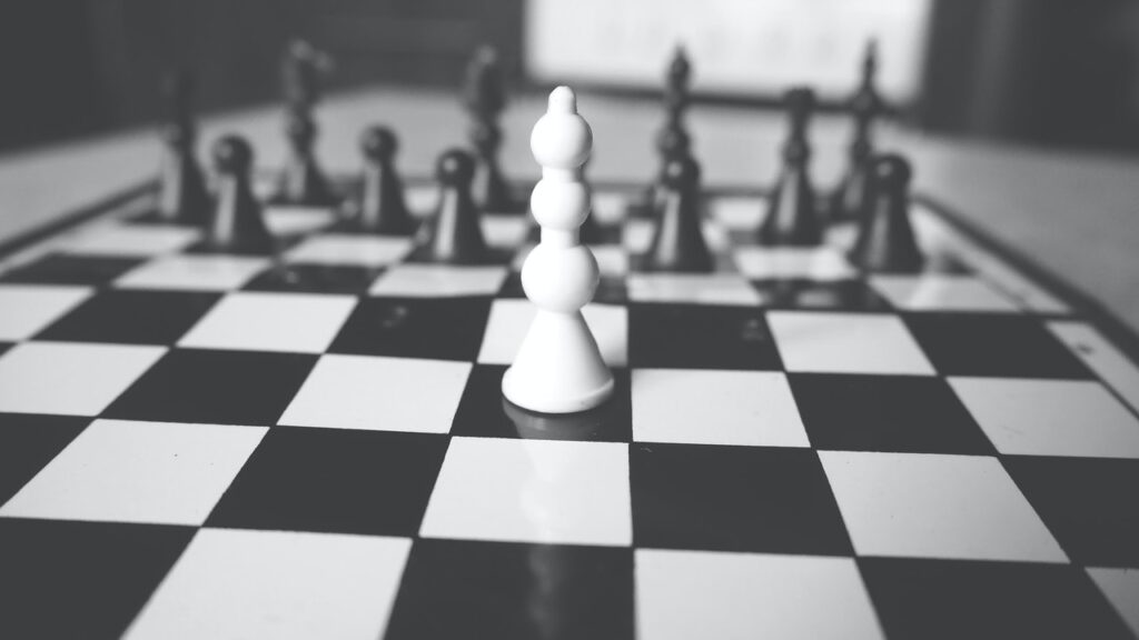 black and white chess board with one white piece against all the black pieces